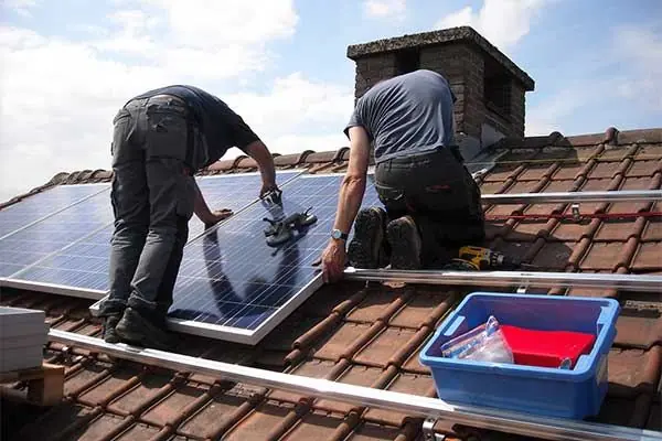 Installers fitting solar panels on a house roof