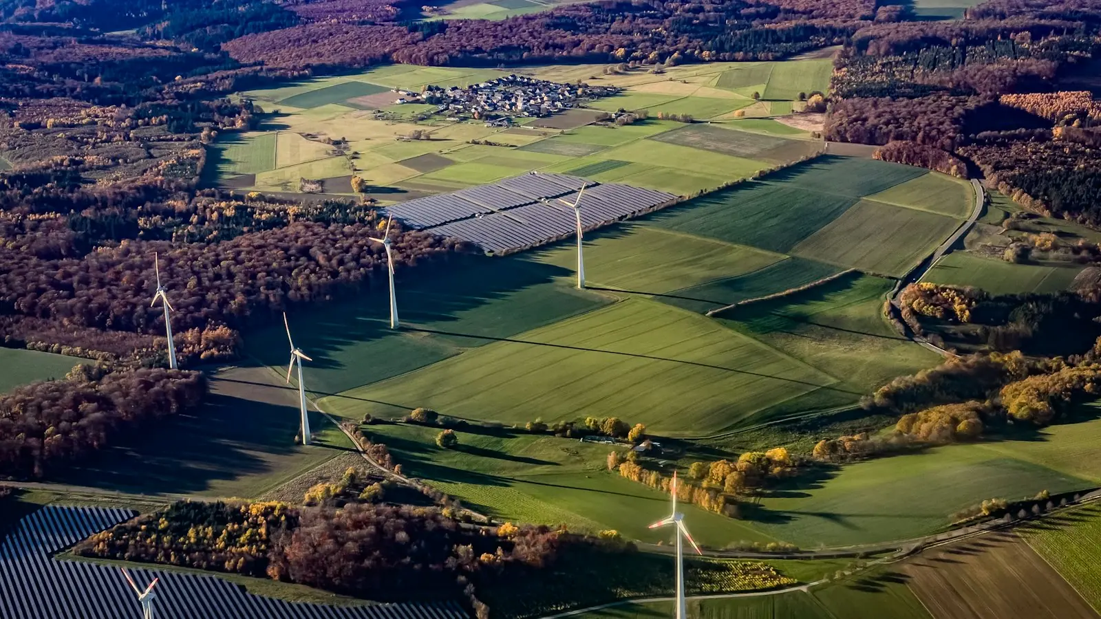 Wind turbines and solar panels across farmland from above